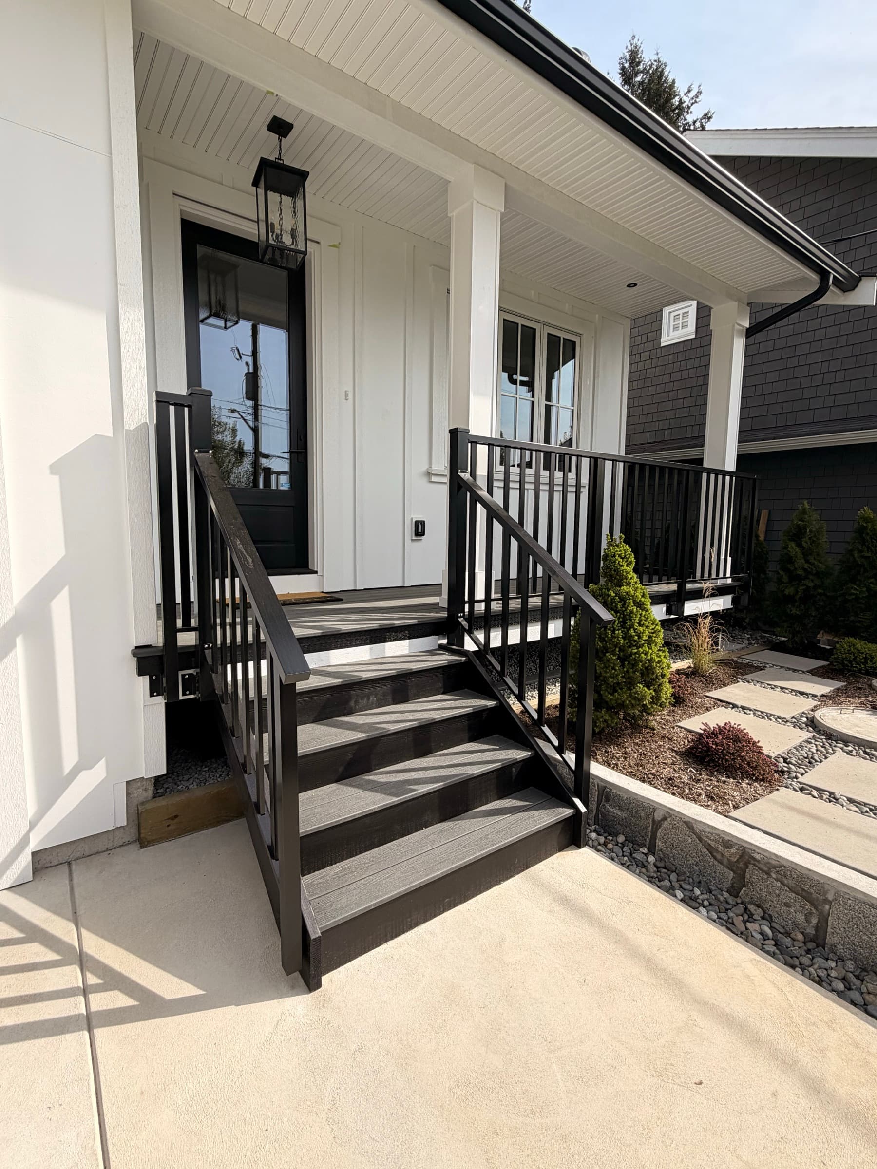 Composite deck with stairs and black railing off a home exterior