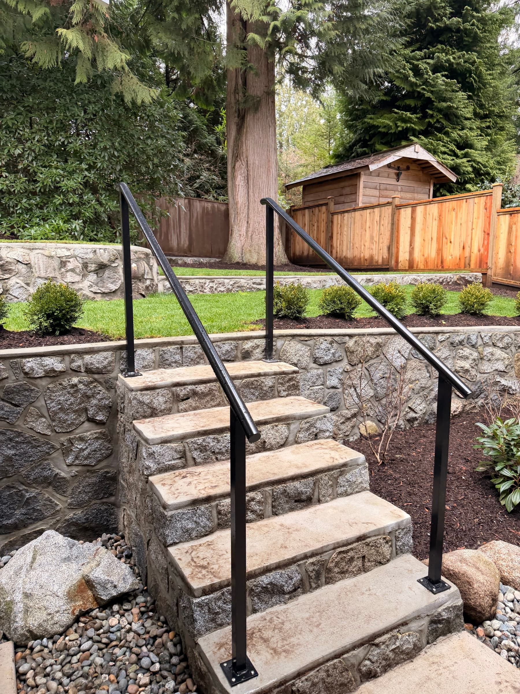 Cedar fence and stone retaining wall along a backyard path